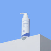 Aestura lotion bottle on a white surface with a blue background
