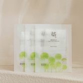 Three sheet masks with green leaf design on a beige background