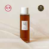 Bottle of skincare product with a label on a beige background, featuring promotional text and an award badge.