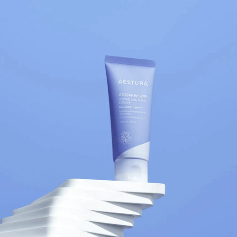 Aestura skincare tube on a white stand with a blue gradient background