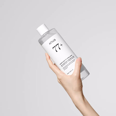 Hand holding a bottle of Artua skincare product on a gray background