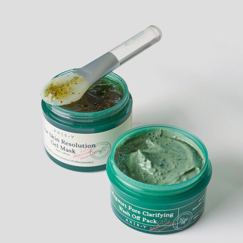 Two green jars of facial mask with a spoon on a white background