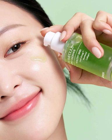 Person applying Ampoule Radiance skincare product to face with a green background