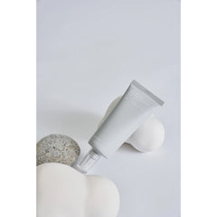 White cylindrical container with a pump on a light gray background