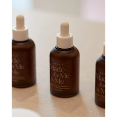 Three bottles of 'Made for Me by Me' serum on a light surface.
