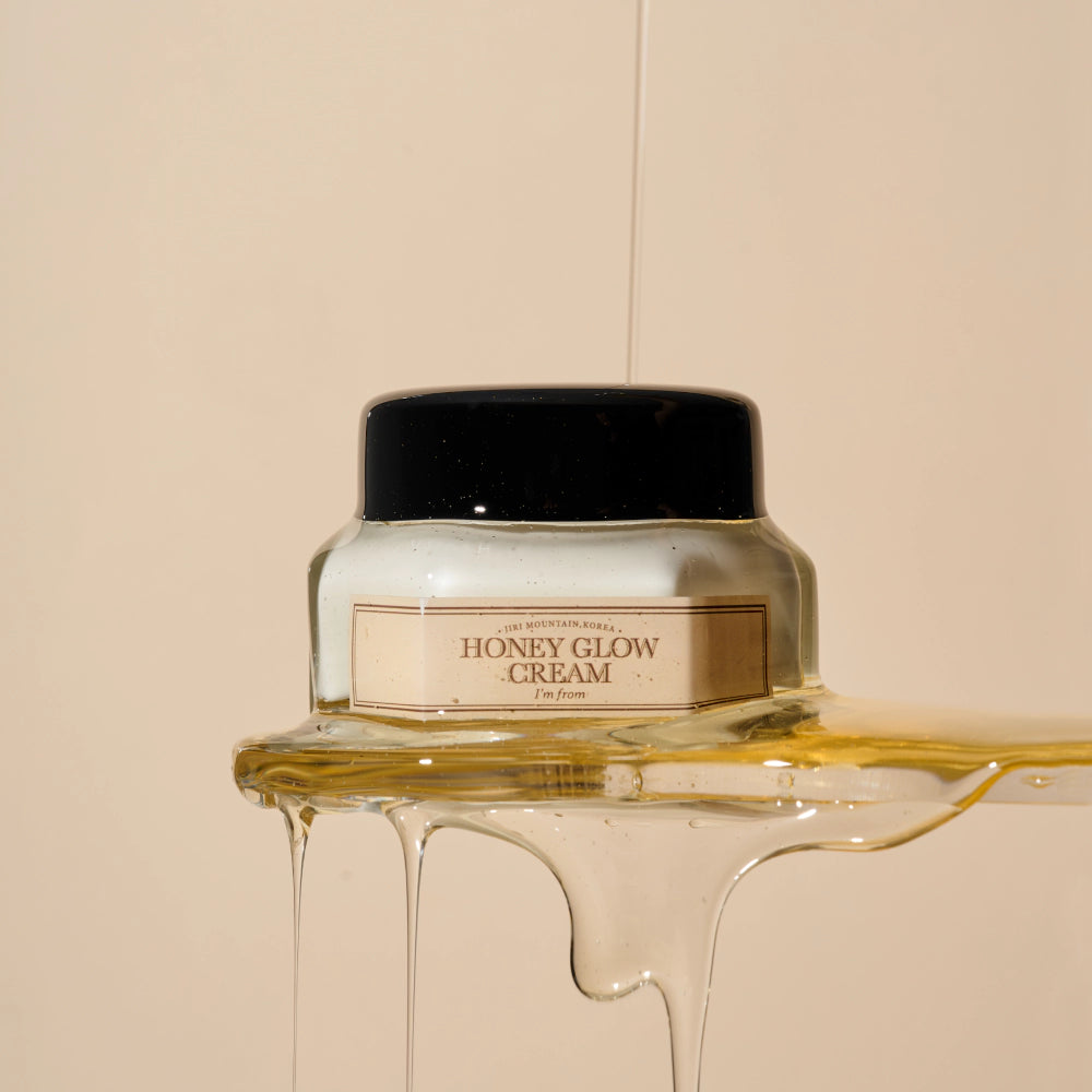 Jar of honey glow cream with honey flowing out on a beige background