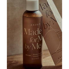 Bottle of AXIS-Y skincare product with a brown label on a wooden surface.