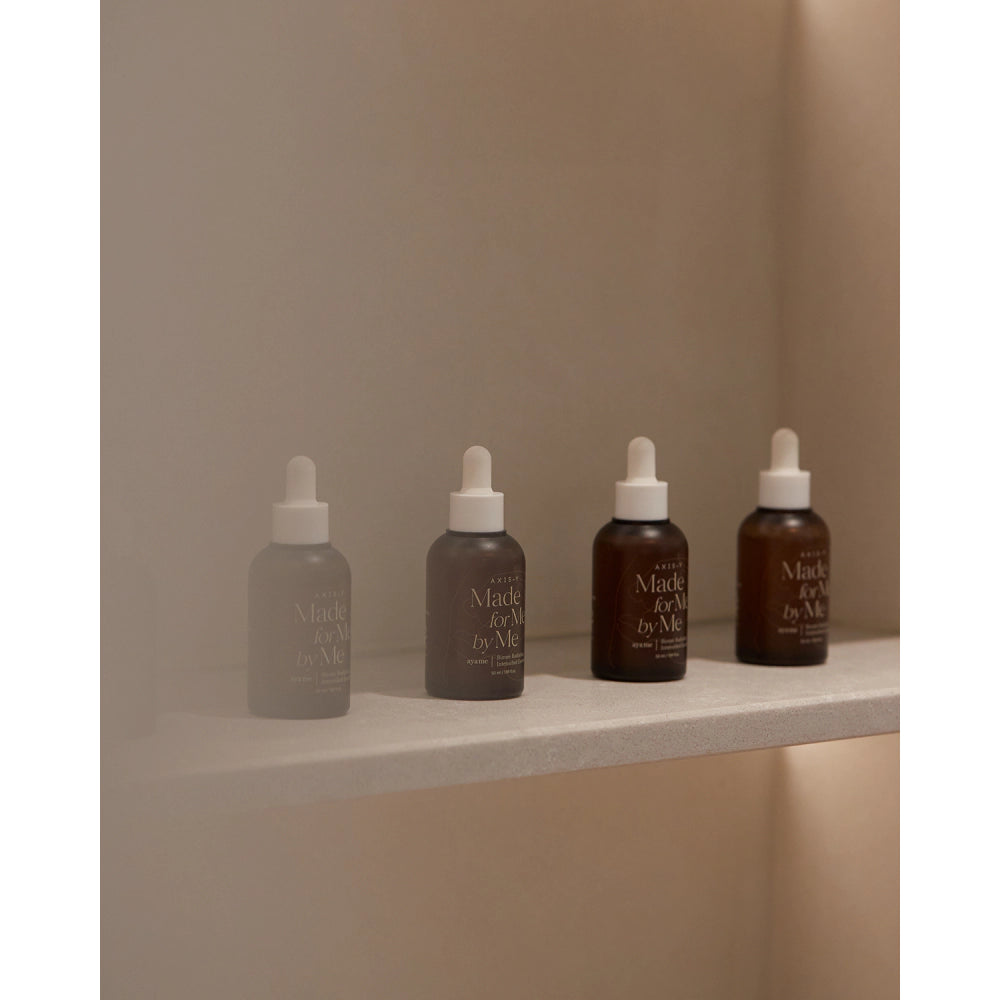 Five skincare bottles with droppers on a neutral background