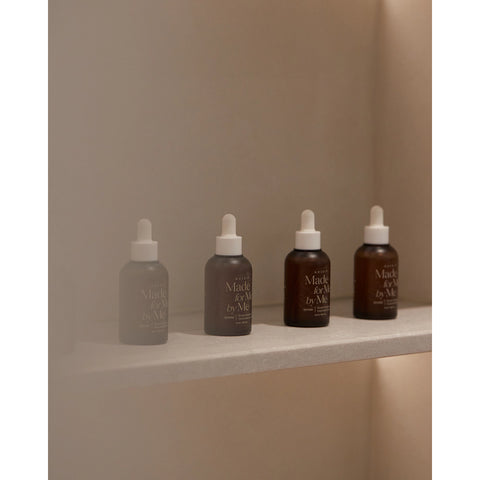 Five skincare bottles with droppers on a neutral background