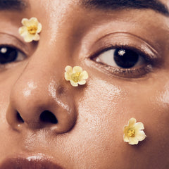 Close-up of a woman's face with flowers on her cheeks