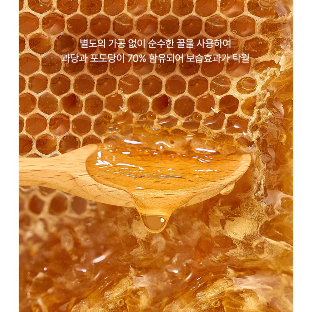 Wooden honey dipper in a honeycomb with honey dripping, on a honeycomb background.