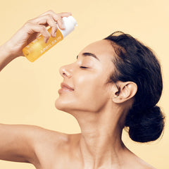 Woman applying April Skin product to her face against a beige background