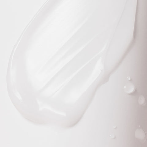 Close-up of white cream or gel texture on a light gray background