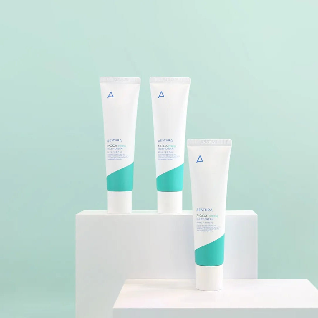 Three skincare products on a white stand against a light blue background