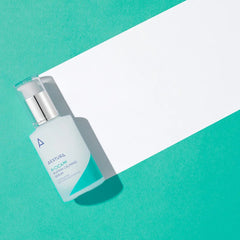 Skincare serum bottle on a teal and white background