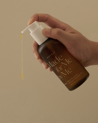 Hand holding a bottle of 'Made for Me' skincare product with a beige background
