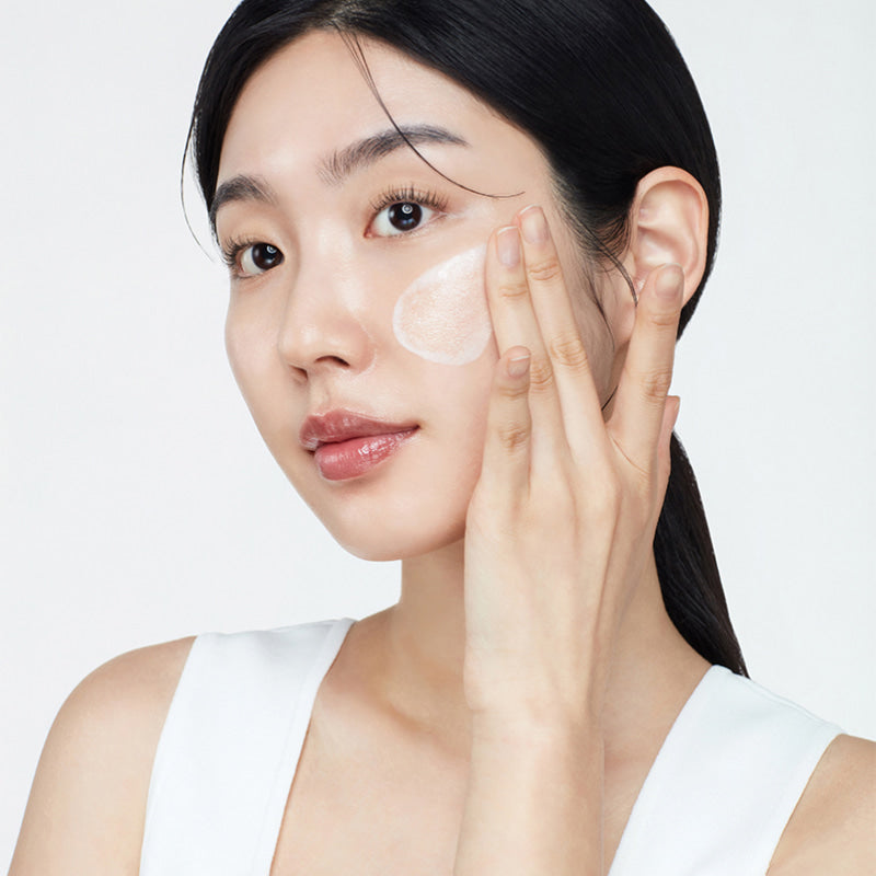 Woman applying cream to her face with a white background