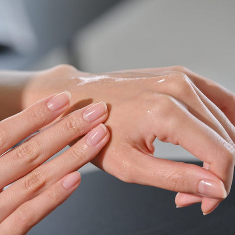 Close-up of hands with clear skin care product on a neutral background
