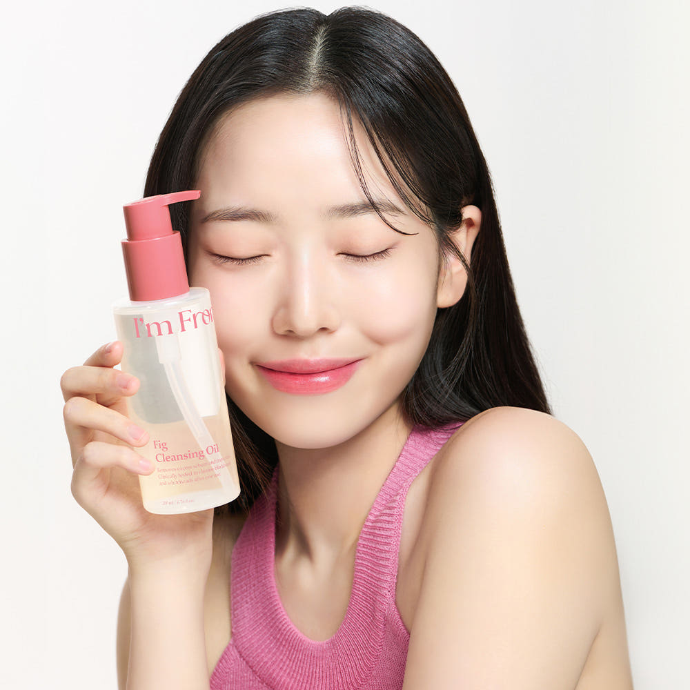 Woman holding a pink skincare product with a white background