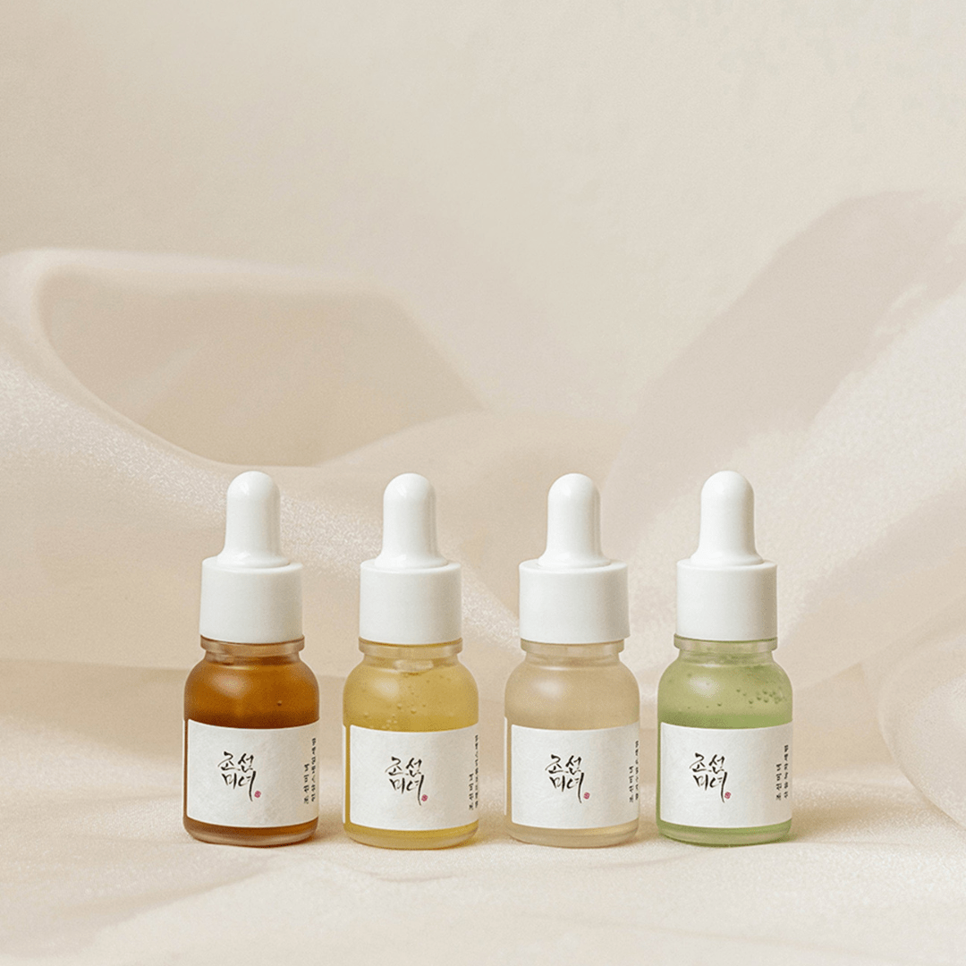 Four dropper bottles with different colored liquids on a soft beige background