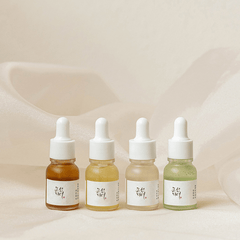 Four dropper bottles with different colored liquids on a soft beige background
