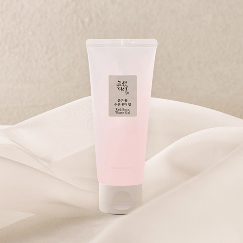 Pink tube of skincare product on a beige fabric background