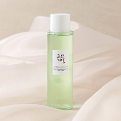 Green bottle of skincare product on a soft beige background