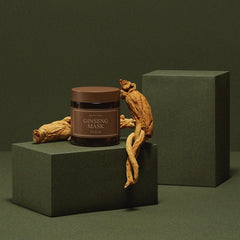 Jar of Ginseng Mask on a green platform with ginseng roots against a dark green background