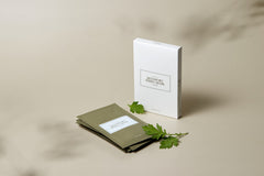 White notebook with green leaves on a beige background