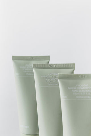 Three green skincare tubes on a light gray background