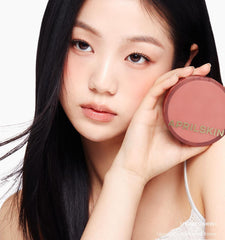 Woman holding a pink makeup compact with 'APRILSKIN' branding.
