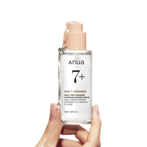 Anua skincare serum bottle held by a hand on a white background