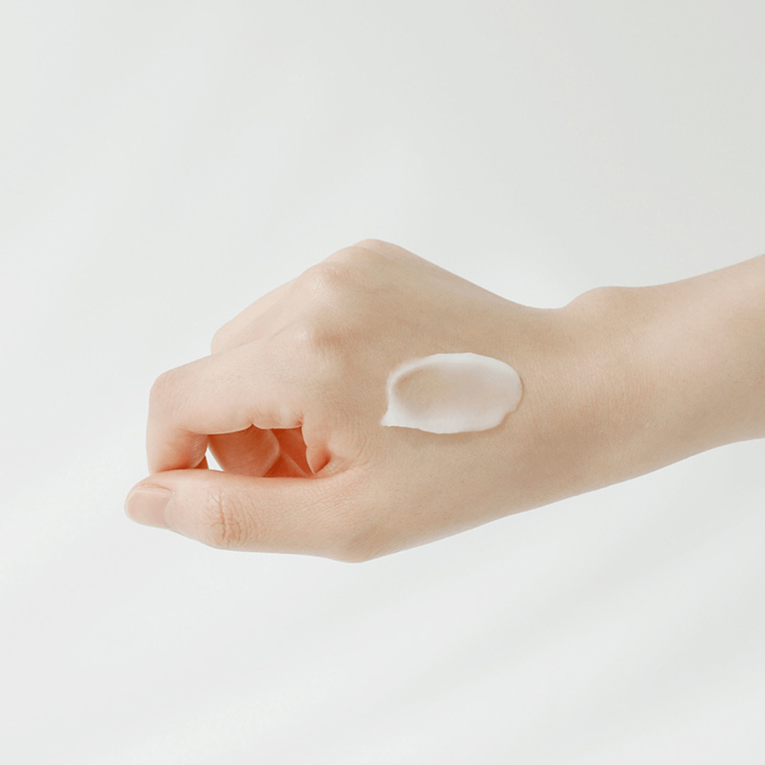 Hand with a small amount of cream on a plain background