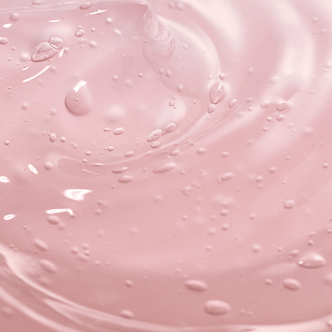 Close-up of pink liquid with droplets and swirls