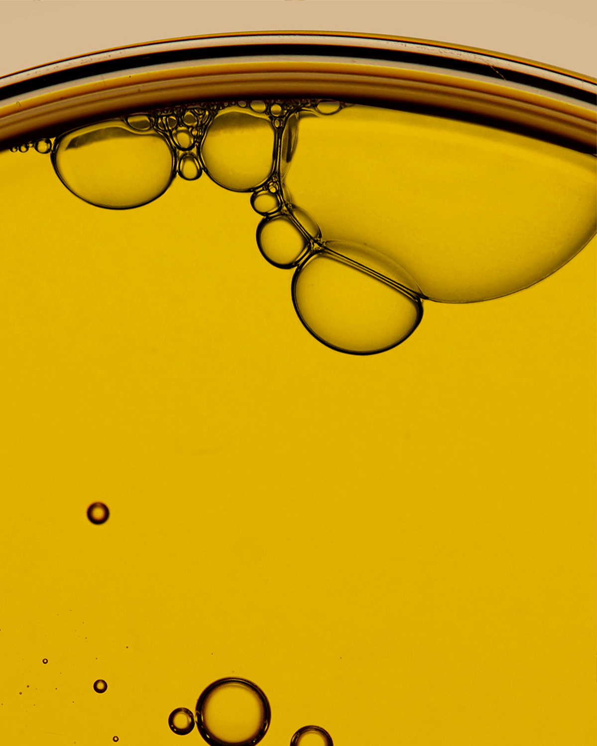 Close-up of oil and water layers with bubbles on a beige background
