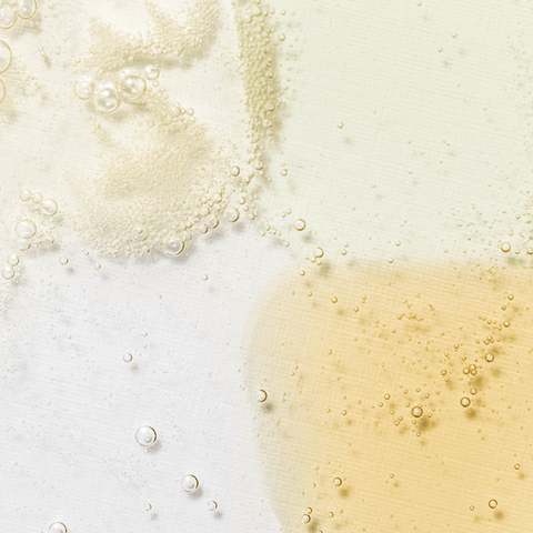 Close-up of bubbles in a liquid with a gradient from white to beige.