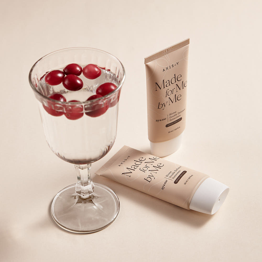 Two tubes of 'Made for Me' skincare product next to a glass with red berries on a beige background