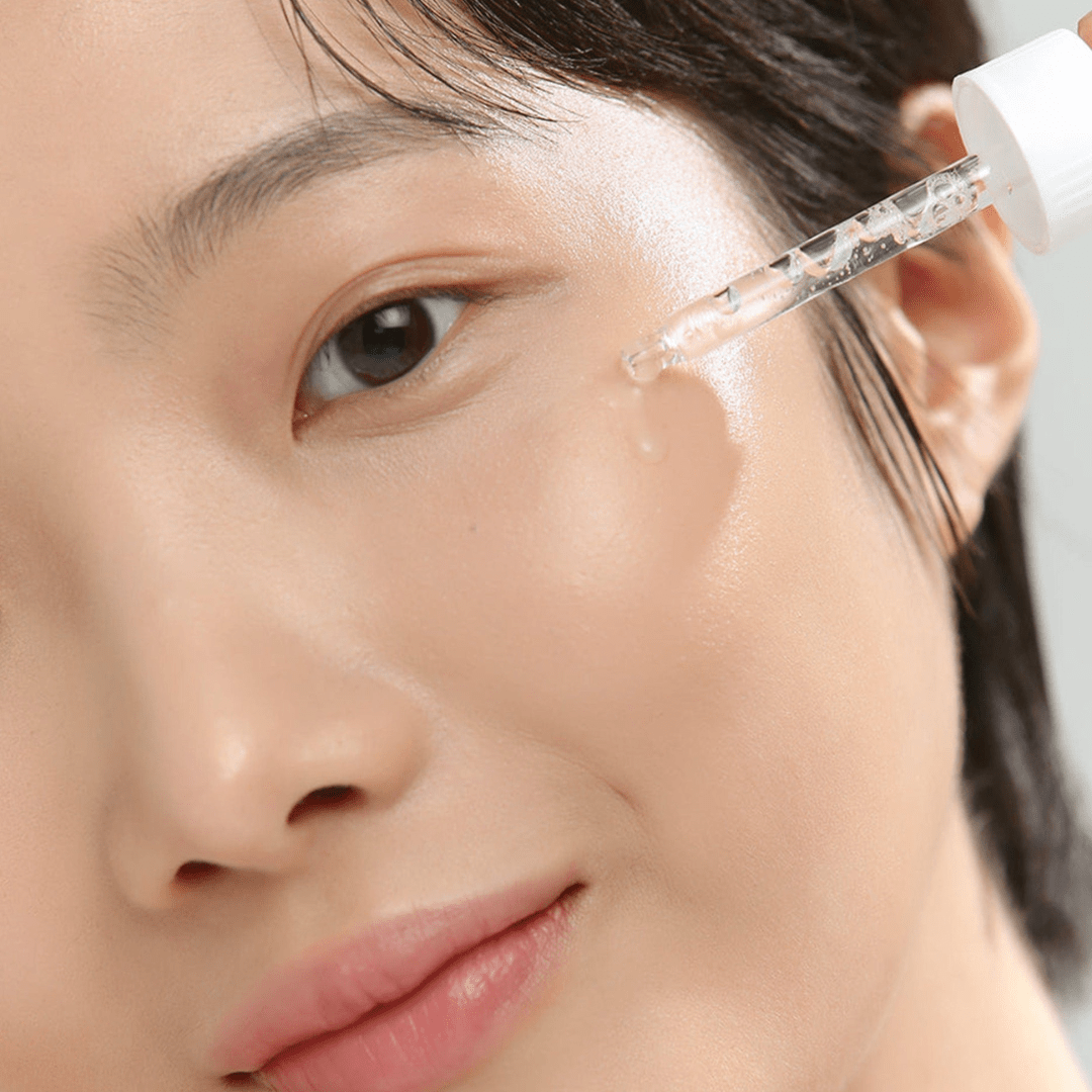 Close-up of a person applying a skincare product to their face.