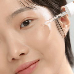 Close-up of a person applying a skincare product to their face.