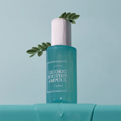 Skincare ampoule bottle with green leaves on a light blue background