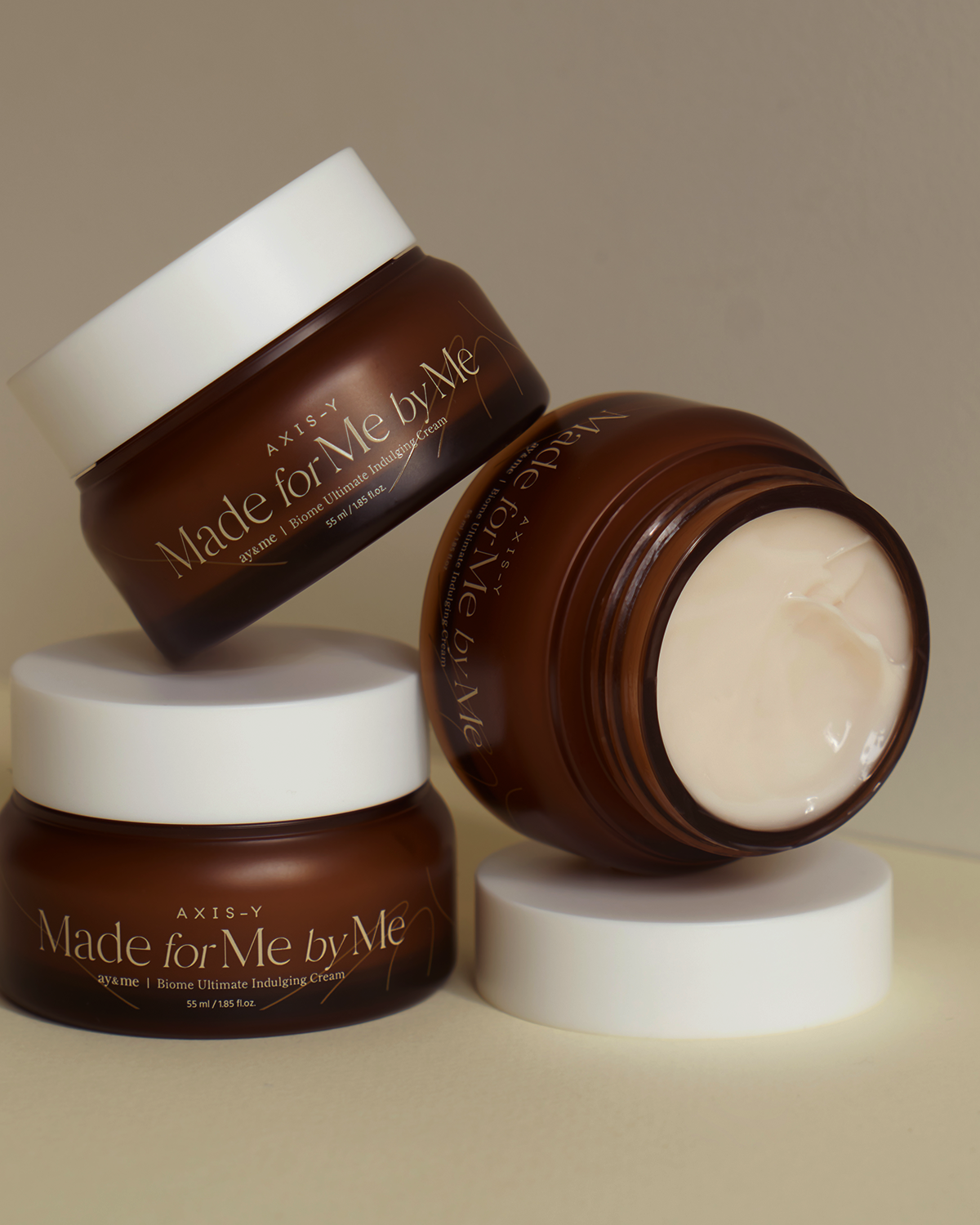 Three jars of 'Made for Me by Me' cream on a neutral background
