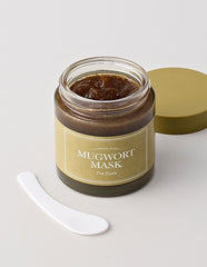 Jar of Mugwort Mask with a white spatula on a light gray background
