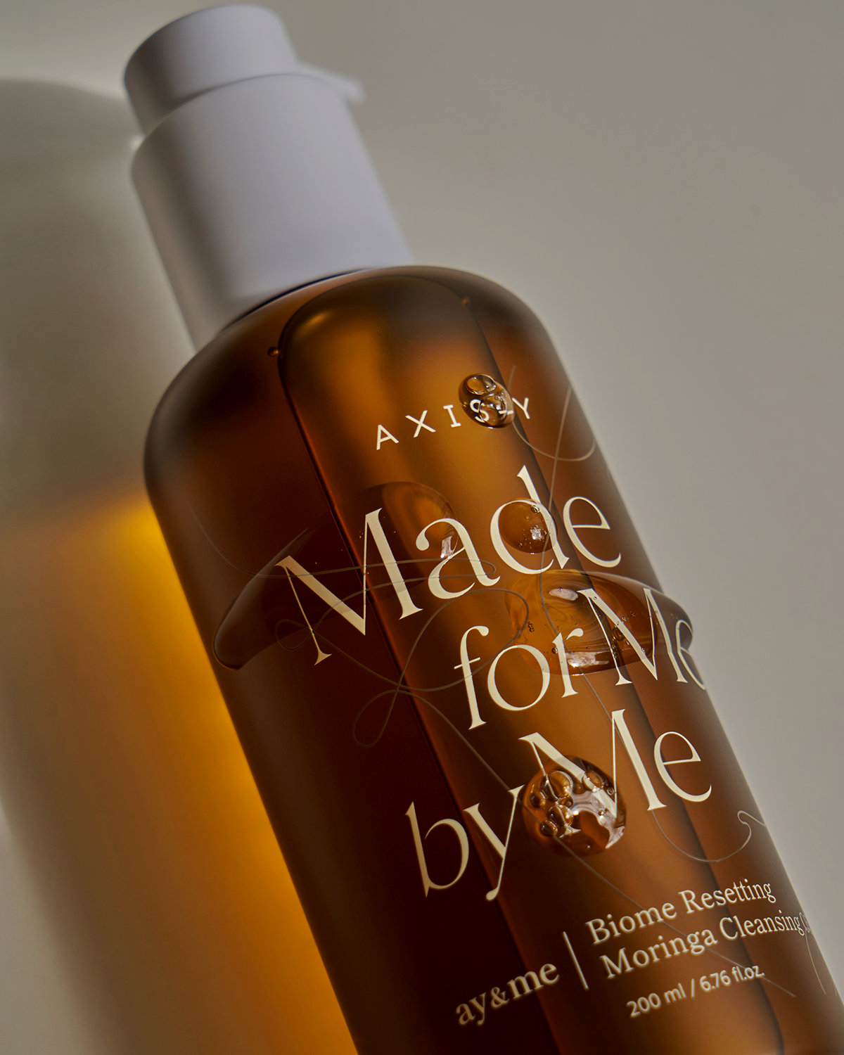 Bottle of Axisay 'Made for Me by Me' skincare product with a white cap on a neutral background.