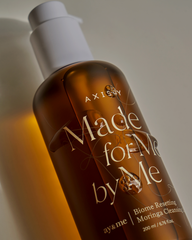Bottle of Axisay 'Made for Me by Me' skincare product with a white cap on a neutral background.