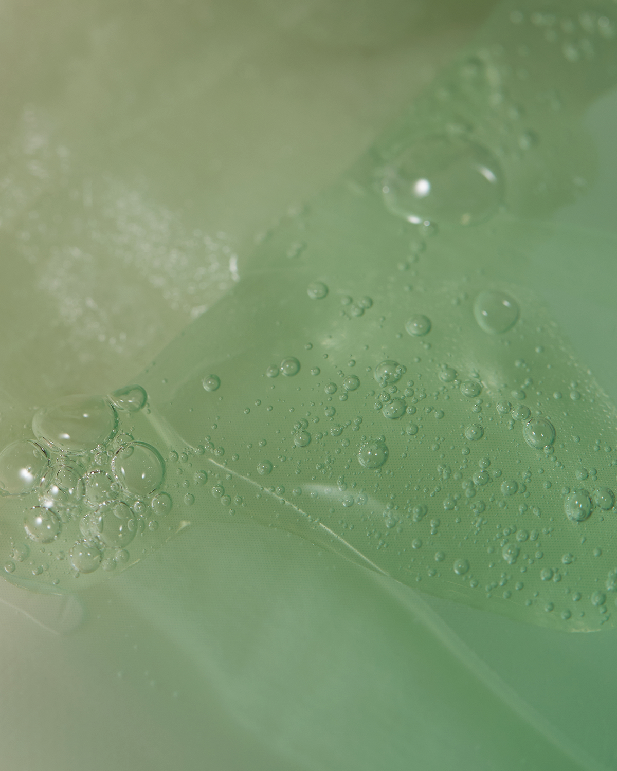 Close-up of a green surface with water droplets and bubbles