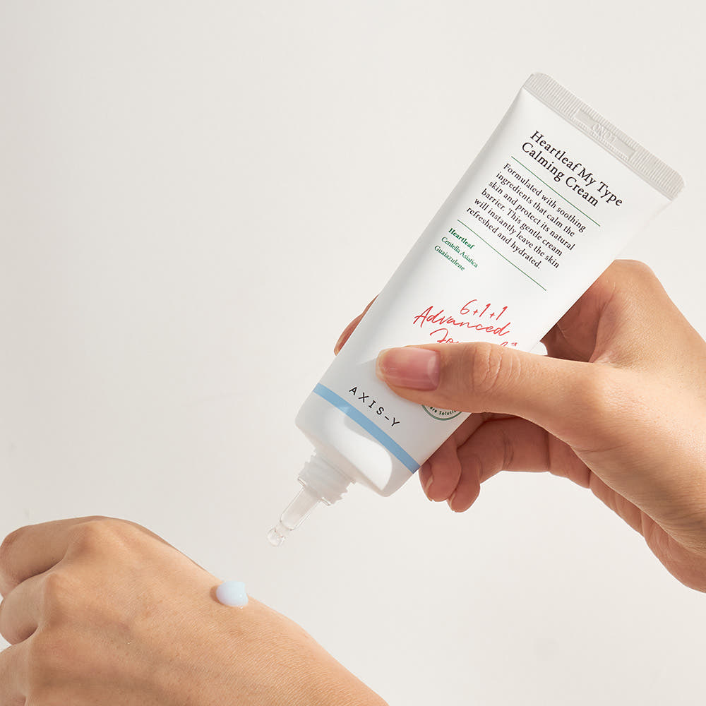 Hand applying AXIS-Y cream to a wrist against a light background