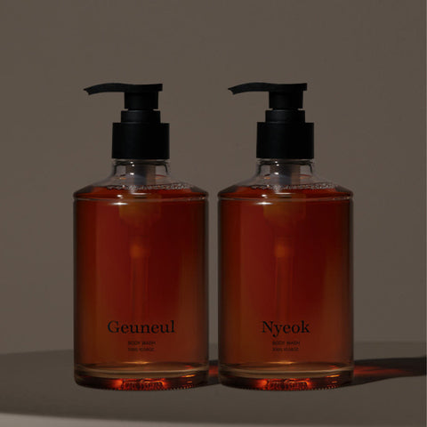 Two bottles of liquid soap with black pumps on a dark background