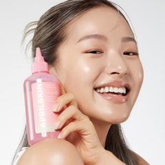 Woman holding a pink skincare bottle with a blurred background