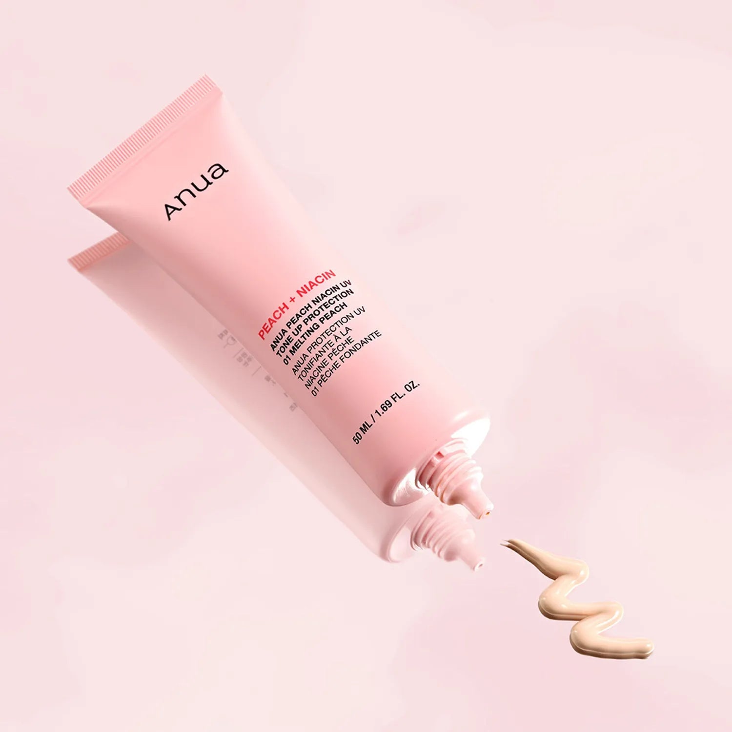 Pink skincare tube with visible brand name on a light pink background