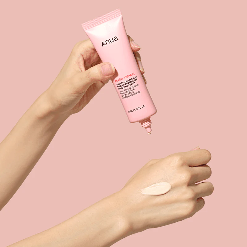 Hand holding a pink Anua product with a swatch on a pink background